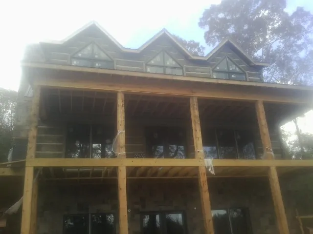 Dormers and porch framing on a large log home under construction — Roof Coating work by our crew in North Branch